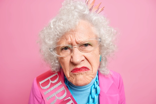 Free photo close up shot of displeased wrinkled woman smirks face looks unhappily, has bright makeup being discontent with something