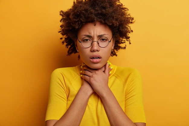 Free photo close up shot of frustrated curly african american woman keeps hands on neck