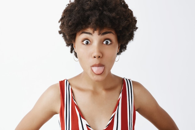 Free photo close-up shot of funny and playful immature stylish woman sticking out tongue and popping eyes fooling around and showing temper while standing