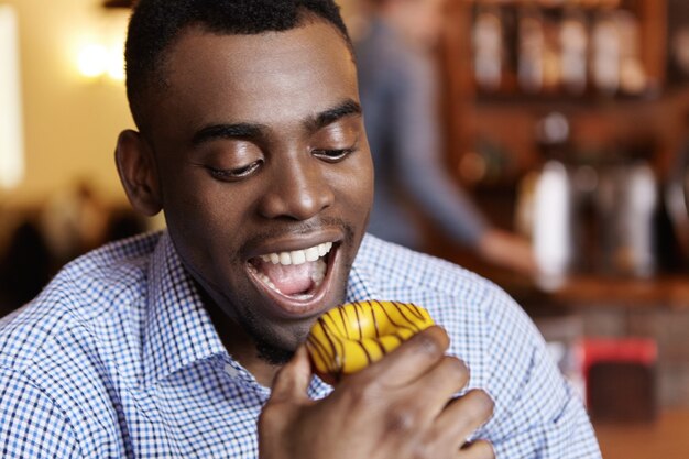 Close-up shot of handsome young dark-skinned man in checkered shirt having tempted look