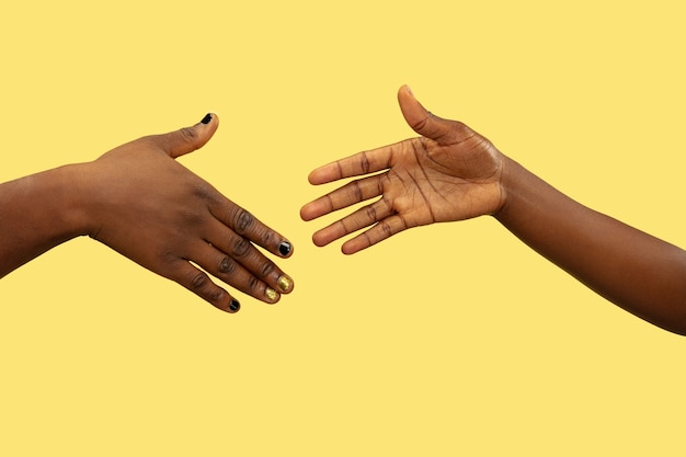 Close up shot of human holding hands isolated on yellow