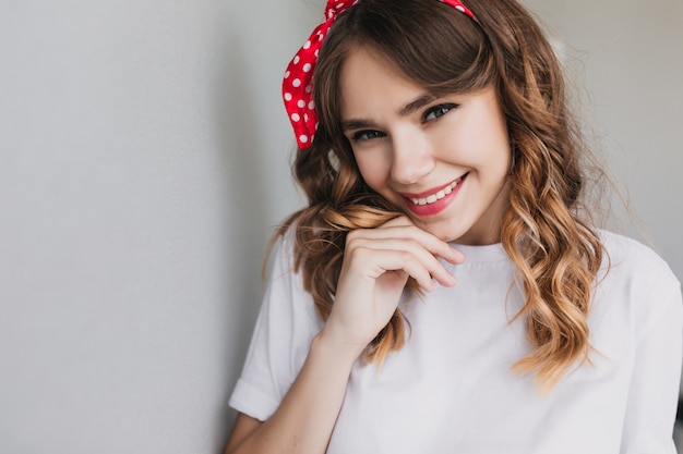 Close-up shot of inspired european young lady posing with smile. Winsome emotional girl with wavy hairstyle laughing