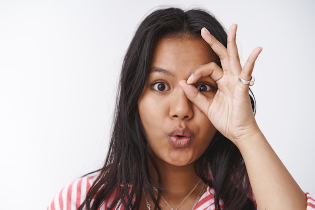 Free photo close-up shot of intrigued and amazed enthusiastic    cute girl showing  ok  gesture over eye