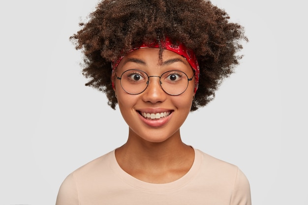 Close up shot of joyful dark skinned woman with positive smile