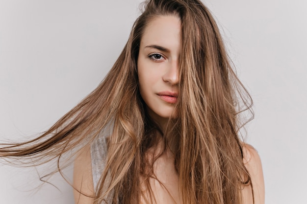 Close-up shot of lovely caucasian girl with pale skin. Indoor portrait of stunning white young woman with long straight hairstyle isolated.