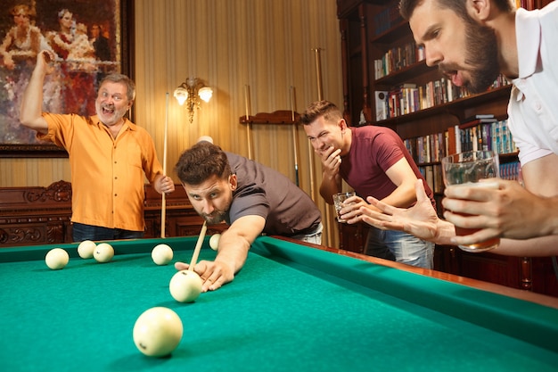 Close-up shot of a man playing billiard. The caucasian model carefully and strenuously aiming by cue in the ball. Game concept.