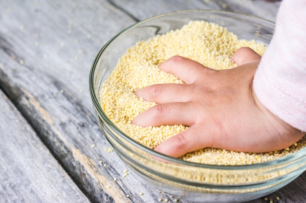 Крупным планом снимок руки ребенка, положенной в миску из свежего цельного зерна амарата