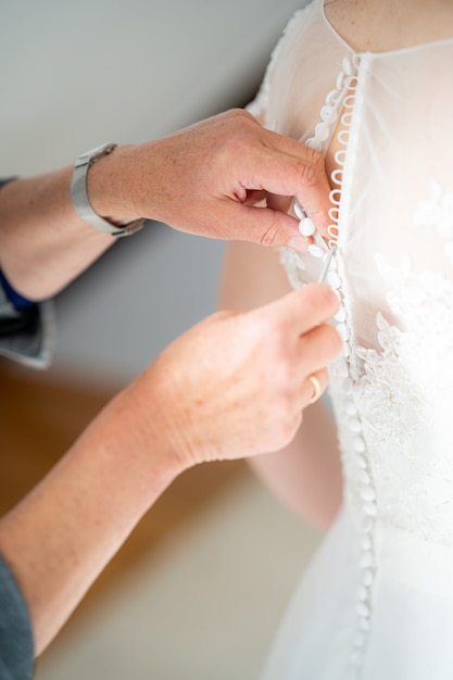 Close up shot of a person helping zip the beautiful wedding dress