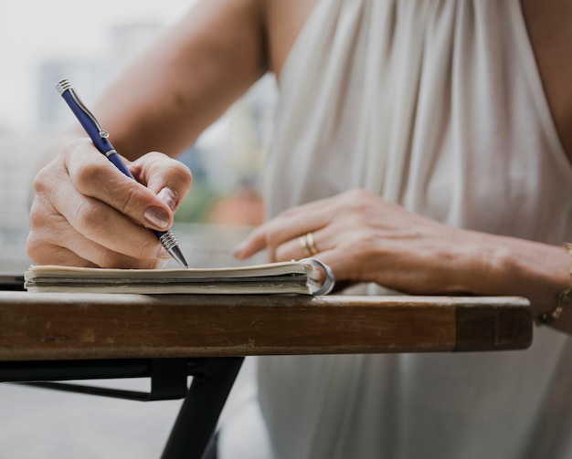 Foto gratuita colpo del primo piano della persona che scrive con una penna sul taccuino