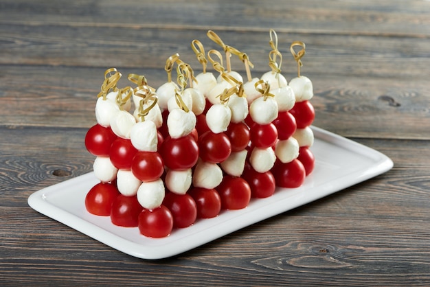 Close up shot of a plate with delicious appetizers cherry tomatoes served with mozarella cheese on the wooden table italian traditional food eating vegetables healthy diet menu restaurant.