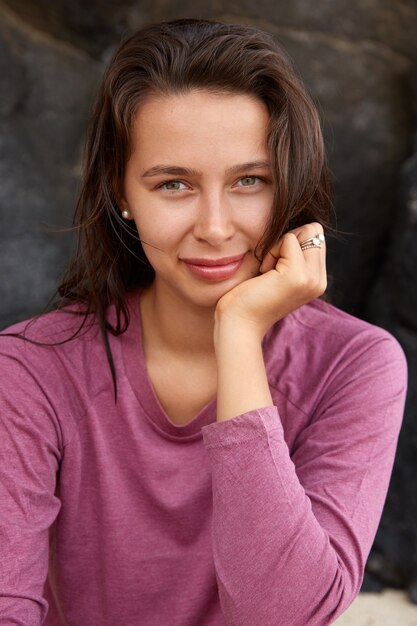 Close up shot of pleased brunette woman has healthy skin