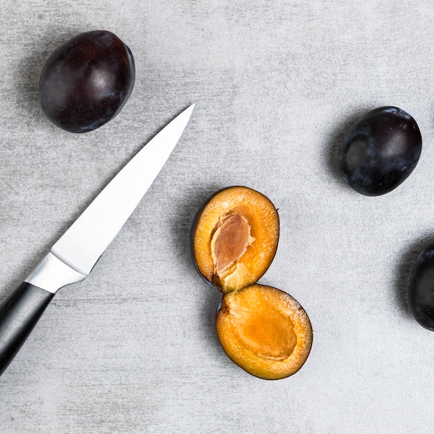 Close-up shot of plums and knife on wooden table