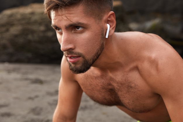 Close up shot of self determined unshaven man looks aside