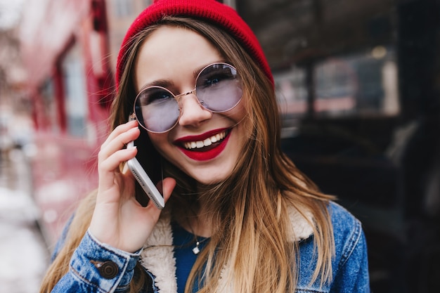 Close-up shot of spectacular woman in red hat calling someone in spring day.