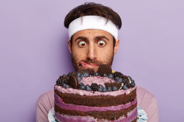 Close up shot of surprised guy stares at delicious cake