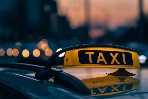 Close-up shot of a taxi sign in the warm colours of sunset with bokeh lights in the background