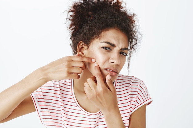 Close-up shot of upset woman with afro hairstyle posing in the studio