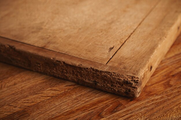 素朴な木製のテーブルの上に横たわっている欠片、深いカットの非常に古くてボロボロのまな板のクローズアップショット