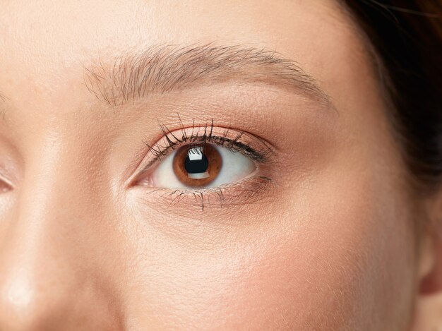 Close up shot of well-kept female big eyes and cheeks on white studio