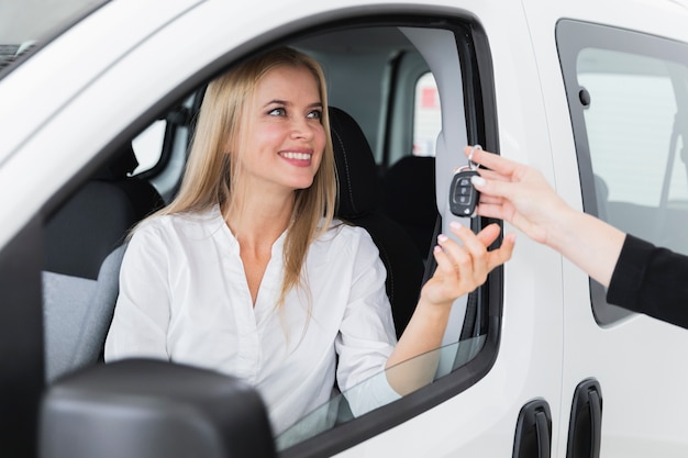 車のキーを受け取る笑顔の女性とのクローズアップショット