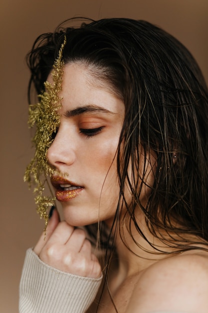 Close-up shot of wonderful pale woman. Sensual female model holding green leaf.