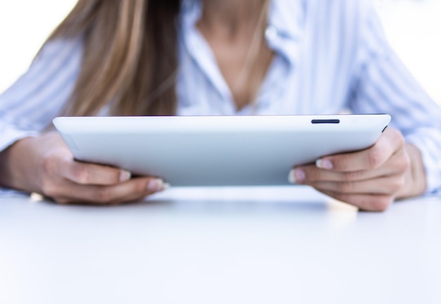 Foto gratuita immagine ravvicinata di una giovane donna in una camicia bianca e blu a righe che lavora su un laptop