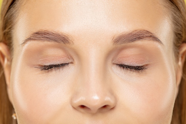 Close up shot of young woman on yellow studio