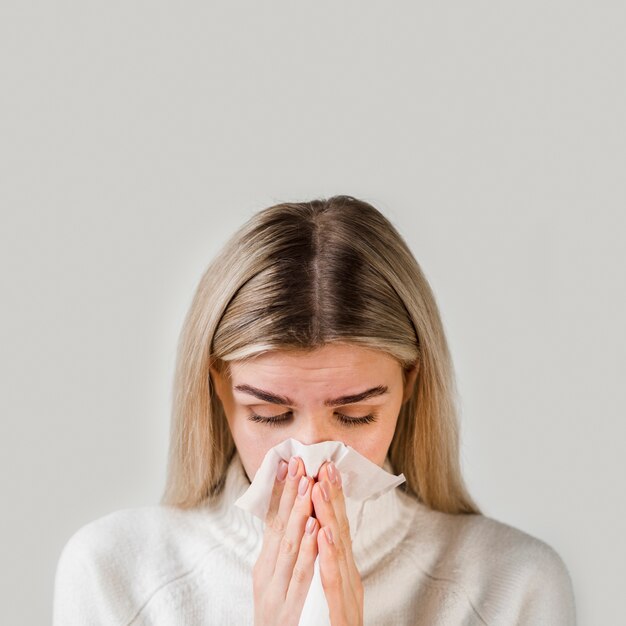 Close-up sick woman blowing nose