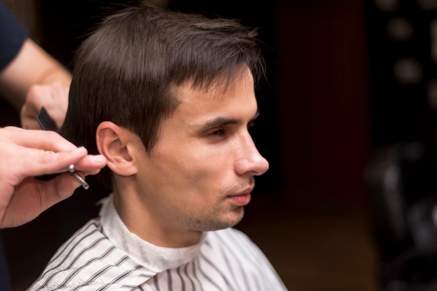 Close up sideways portrait of a man getting a haircut