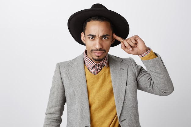 Free photo close-up of skeptical african-american man looking with dismay, roll finger over head