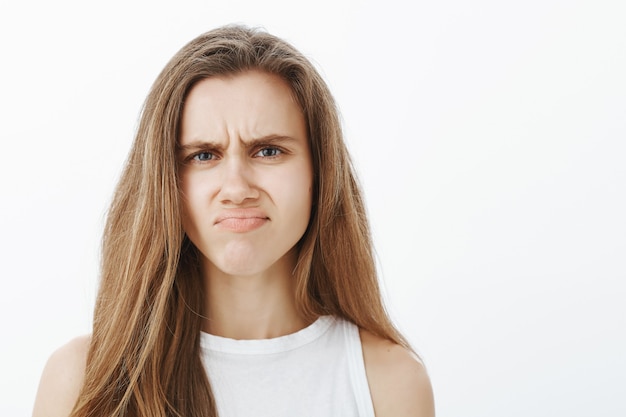 Close-up of skeptical and disappointed, grimacing attractive girl, shaking head and frowning displeased