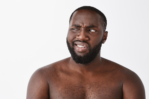 Free photo close-up of skeptical and displeased young guy posing against the white wall