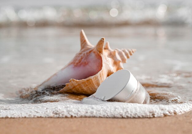 Close-up of skin care moisture recipient arrangement next to seashell