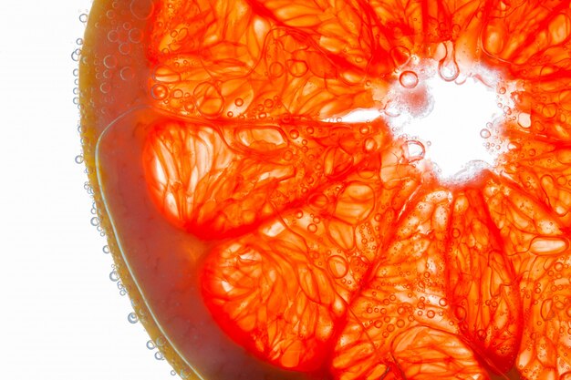 Close-up of slice of grapefruit with ait bubbles on juicy fibers