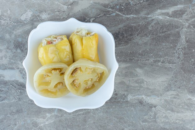 Close up of sliced tomato and filled pepper pickle in white bowl