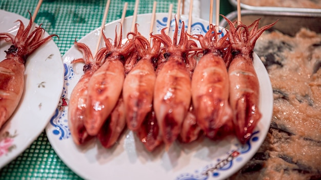 小さな​イカ​の​グリル​、​日本食​旅行​、​料理​を​クローズアップ​。​棒​の​上​の​小さな​タコ​は​、​京都​の​シーフード店​で​おいしい​伝統的​な​日本​の​ストリート​スナック​です​。​販売​の​ため​の​魚市場​の​屋台