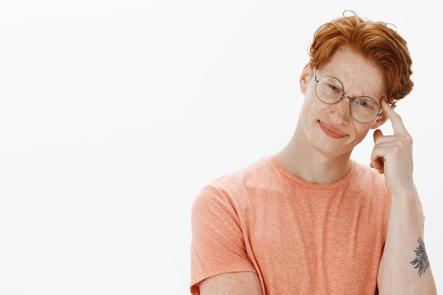 Close-up of smart and attractive male student, man in glasses pointing at head, giving hint to think about