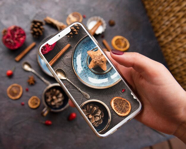 Крупный план смартфона на вершине печенья с сушеными цитрусовыми и сосновыми шишками