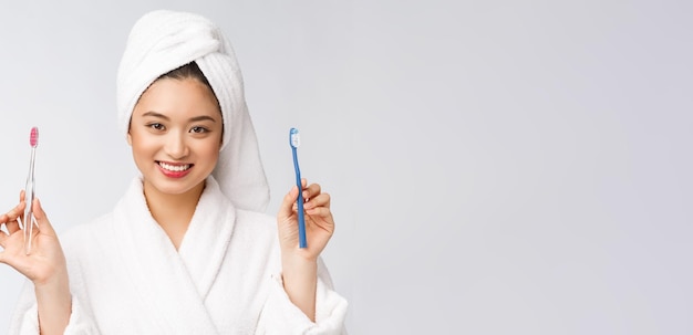 Крупный план улыбающейся женщины чистит зубы отлично подходит для концепции здравоохранения стоматологической помощи, изолированной на белом фоне азиата