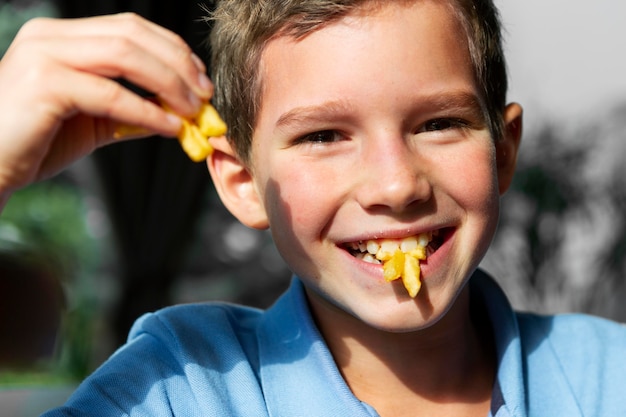 フライドポテトを食べる笑顔の少年をクローズアップ