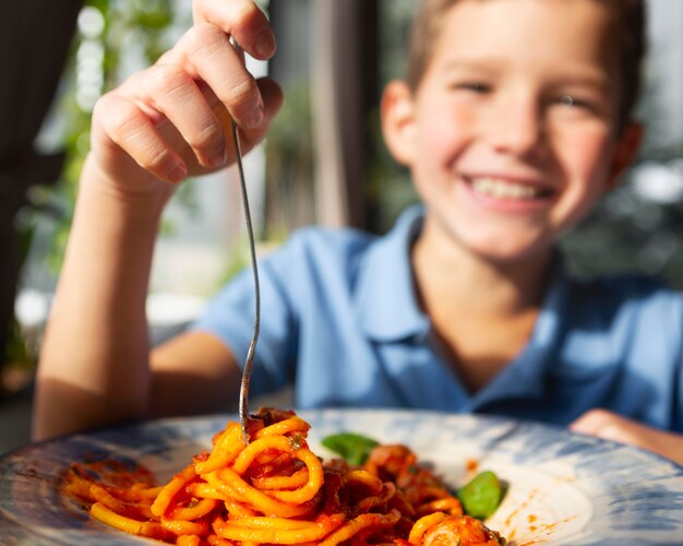 Close up smiley boy eating spaghetti