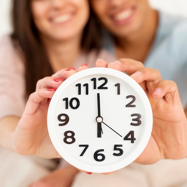 Free photo close-up smiley couple with clock