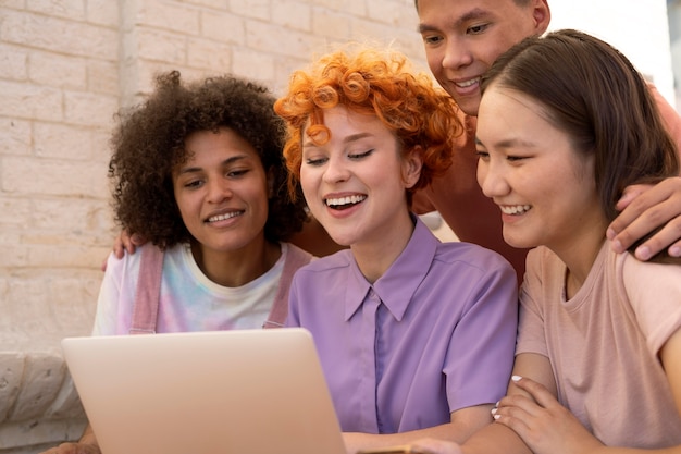 Chiuda in su gli amici sorridenti con il laptop