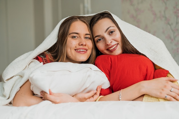 Free photo close-up smiley girls under a blanket