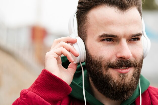 Close-up smiley guy with headphones looking away