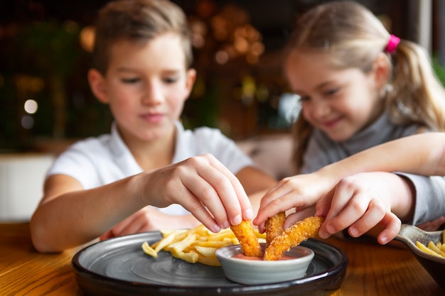 Free photo close up smiley kids eating fast food