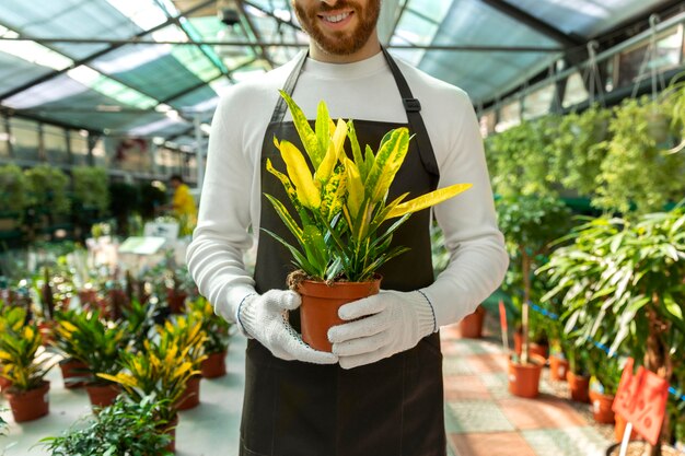 Крупным планом смайлик мужчина держит растение