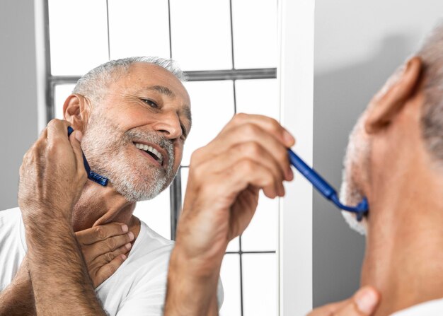 Close-up smiley man shaving in mirror