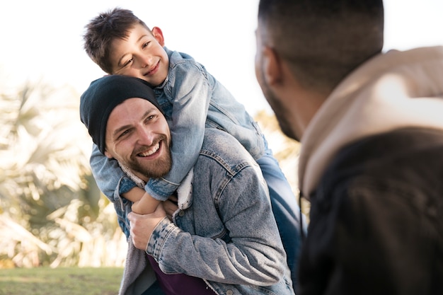 Chiuda in su uomini sorridenti con bambino