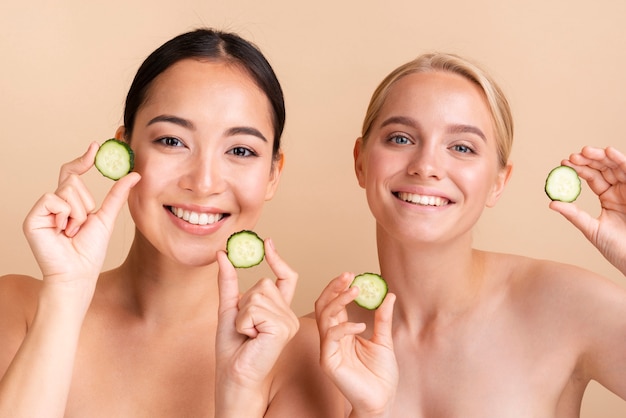 Free photo close-up smiley models posing with cucumber slices